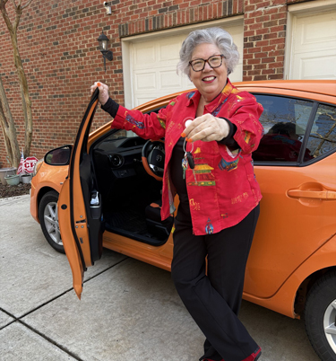 Lady with car keys in her hand in front of the orange vehicle